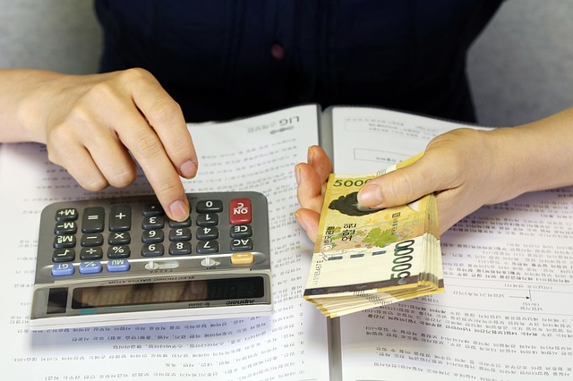 žena držící balíček peněz a počítající na kalkulačce